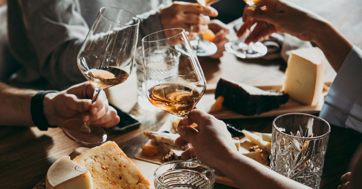 People cheersing glasses of wine with food on the table