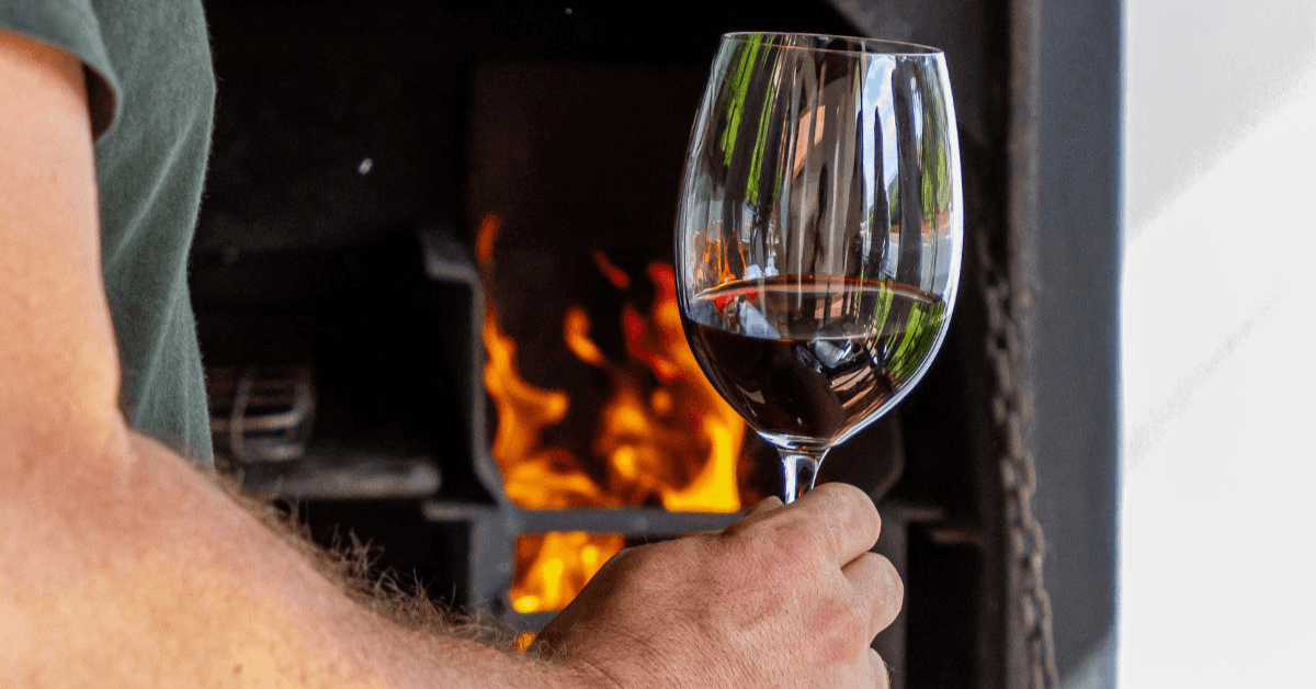 Man holding a glass of wine in front of a private outdoor braai area at D'Aria Winery 