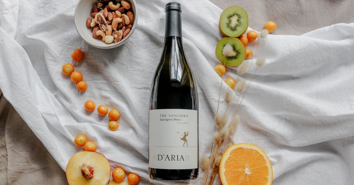 Wine club south africa - D'Aria The Songbird Sauvignon Blanc laid out on a white sheet with fruits around it
