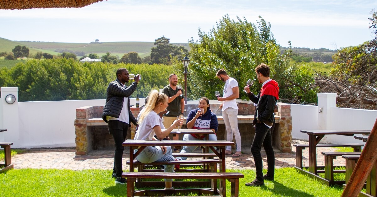 Friends standing outside having a braai with a glass of wine