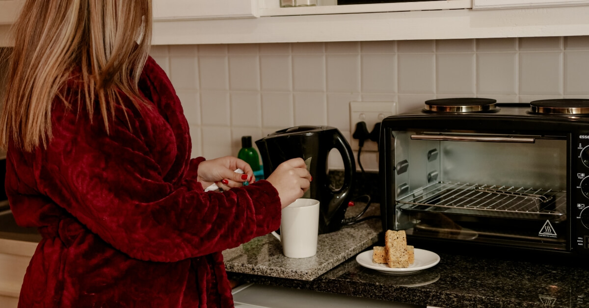 Lady in a gown stirring a cup of coffee with a plate of rusks next to her cup